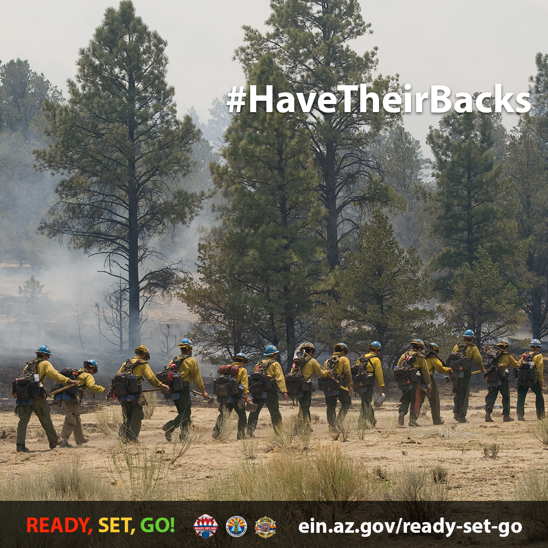 The image shows wildland firefighters lined up in a row. 