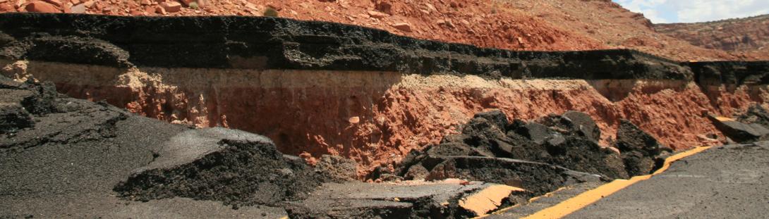 Cracked roads and crumbled dirt and rocks as evidence of landslides.