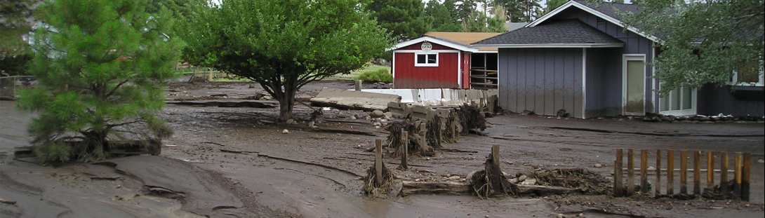 Remnants of flooding in Northern Arizona showing the level of flood water and silt on the house and surrounding areas.